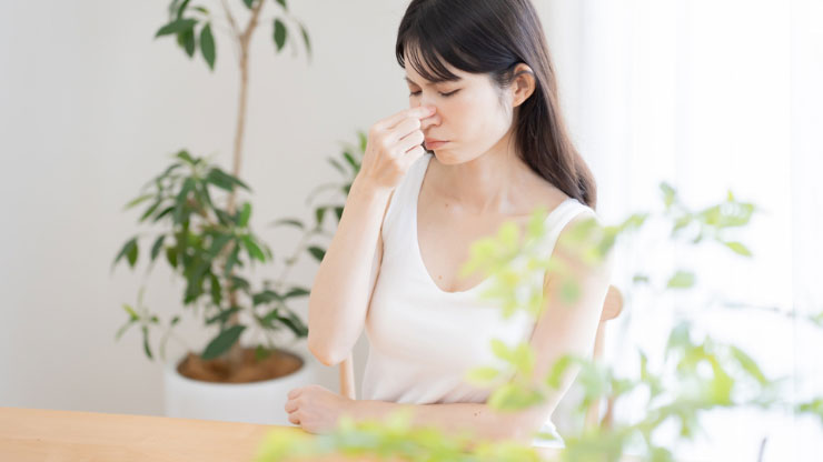 鼻をつまむ女性